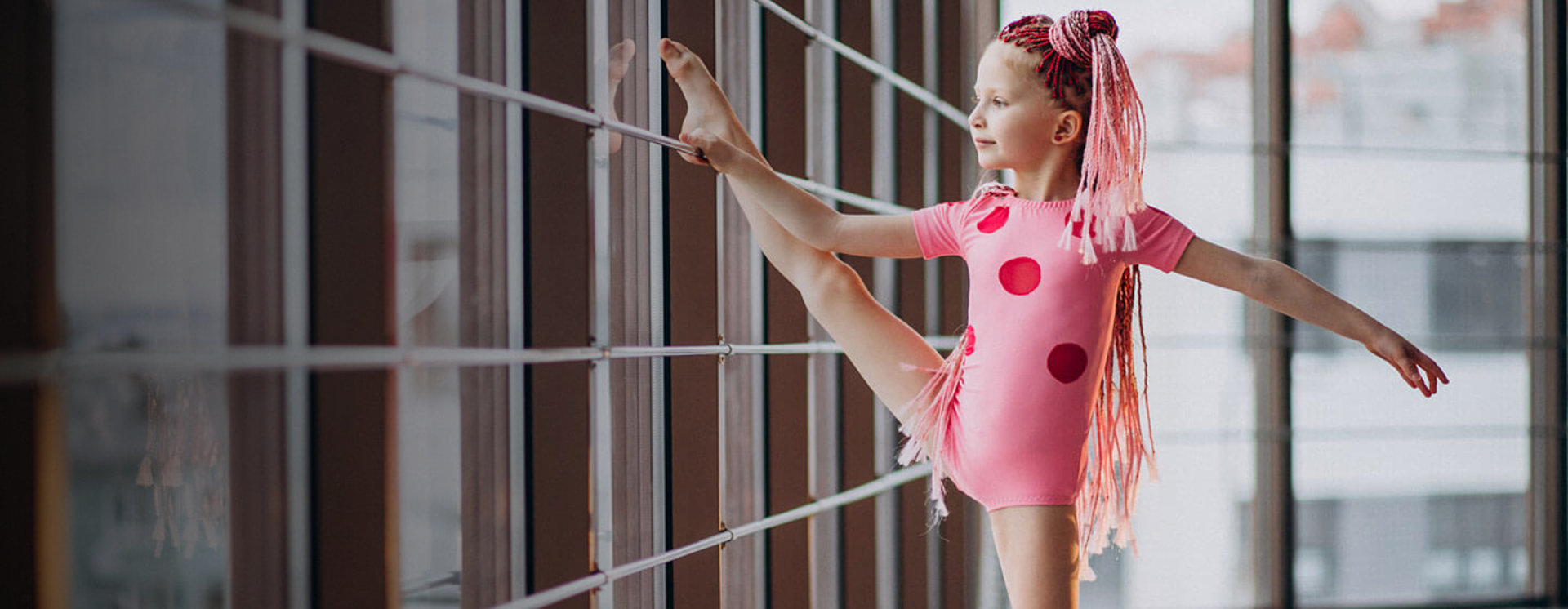 A young girl is doing a split stretch.