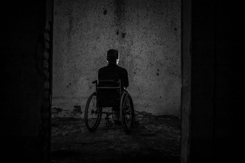 man sitting on wheelchair on a dark environment